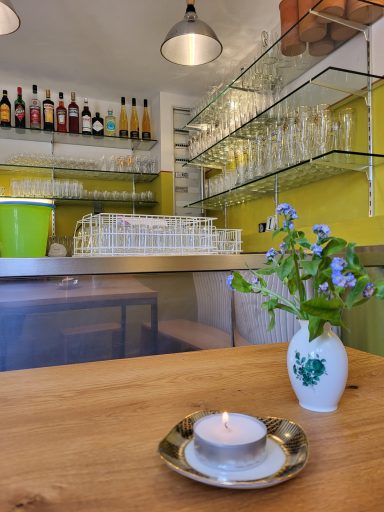 In der Bar an dem Tisch. Blick auf die Theke. Auf dem Tisch eine Blume und Kerzen auf einem kleinen Teller