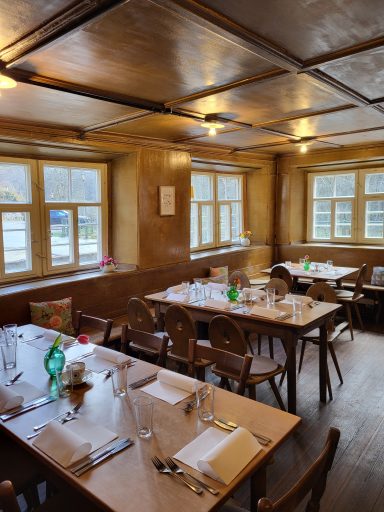 Blick von der Tür in die Stube. Es sind drei eingedeckte Tische zu sehen