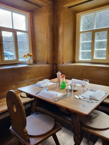 Eingedeckter Tisch in der Stube links in der Ecke. Servietten, Besteck, Gläser und Blumenschmuck